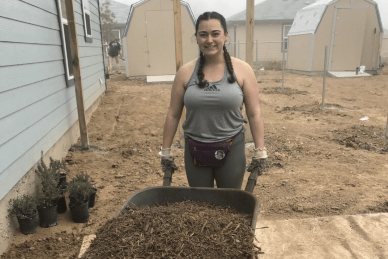 Student moving mulch in field work day.