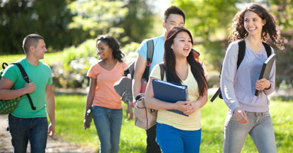 Visually diverse students walking with books in hand or bookbags