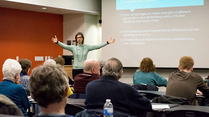 Professor Amy Lorek presenting in front of a group of individuals with a PowerPoint behind her